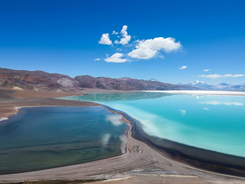 Laguna turquesa de altura con cerros y nubes